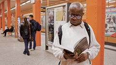 Ein Mann liest in einem Buch in einer U-Bahnstation