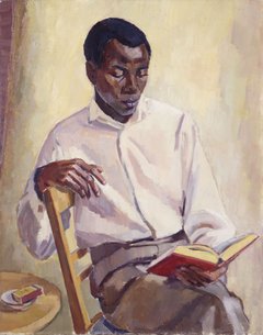 ein junger Mann sitzt auf einem Stuhl und liest ein Buch