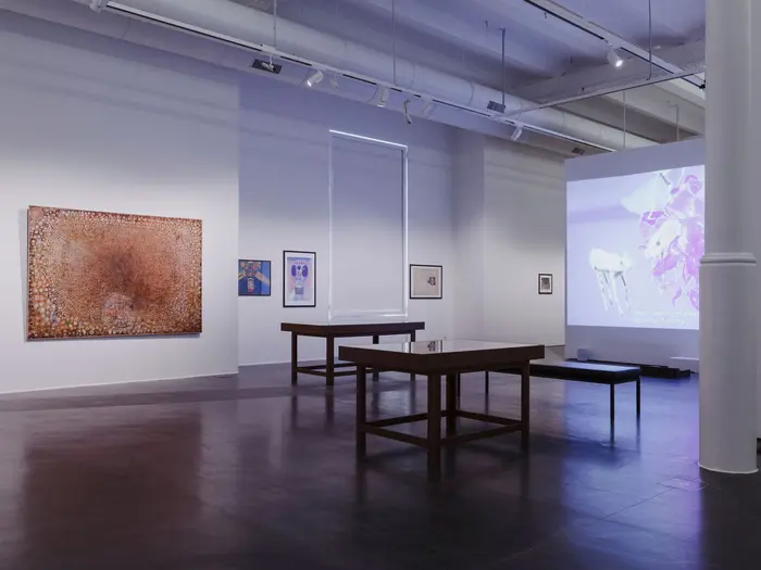 Eine Ausstellungsansicht mit Gemälden und einer Videoarbeit