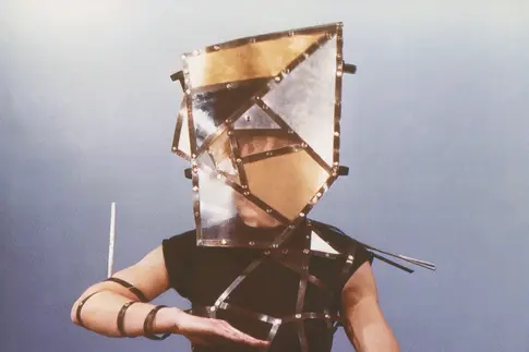 Person in dunklem Kostüm mit Nietengurt und Scheiben