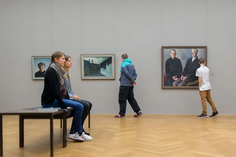 Zwei Frauen auf einem Sitzbank in einem Ausstellungssaal 