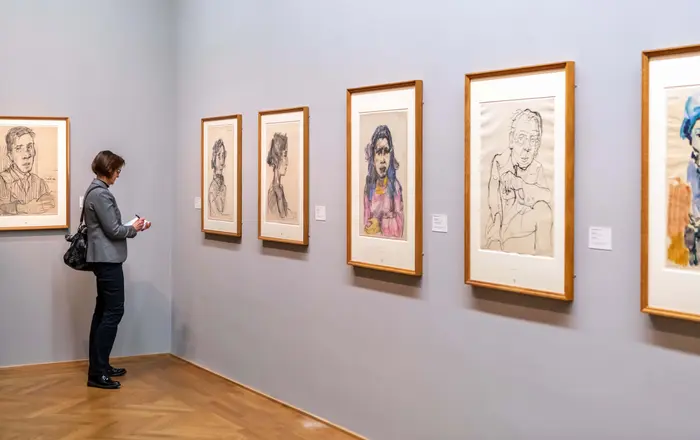 Eine Frau steht im Ausstellungsraum und notiert etwas.