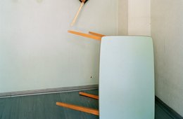 Kerstin Flake, Fake Spaces 04, 2006 Foto mit einem umgekippten Tisch und einer Malerpalette an der Wand