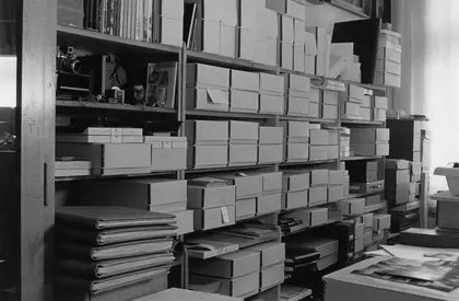 Schwarz-Weiß-Fotografie eines Regals mit Boxen und Mappen.