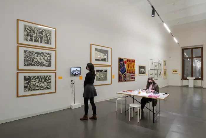 Eine Ausstellungsansicht mit Gemälden und Besucherinnen 