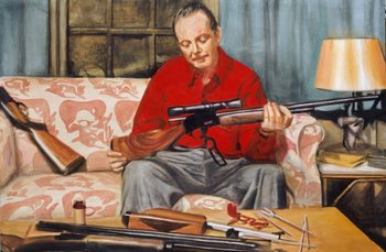 ein Mann im roten Hemd sitzt auf der Couch und reinigt ein Gewehr