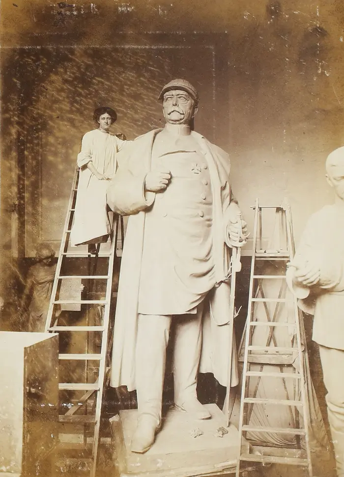 Eine Frau steht auf einer Leiter neben einer großen Statue