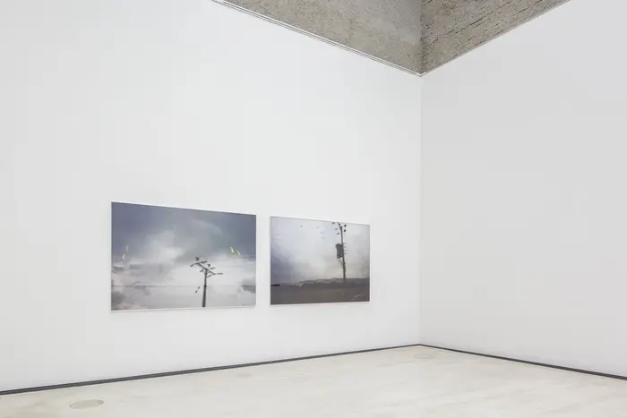 Eine Ausstellungsansicht mit zwei Fotos an der Wand