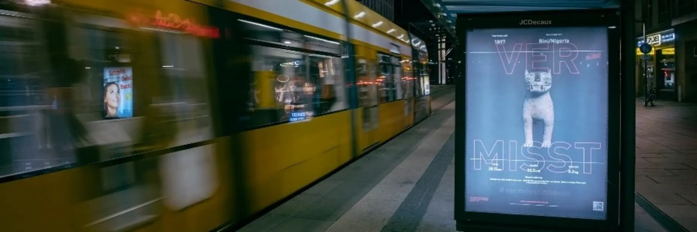 Eine Haltestelle mit Straßenbahn und einem Plakat mit der Aufschrift "Vermisst"