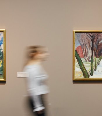 Ausstellungsansicht "Paula Modersohn-Becker und Edvard Munch. Die großen Fragen des Lebens" zwei Bilder an der Wand und eine Besucherin