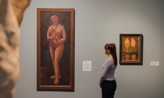 angeschnittene Skulptur und zwei Bilder an der Wand mit einer Besucherin