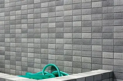 Wand aus Ziegeln, in einer Einbuchtung ein Schlauch
