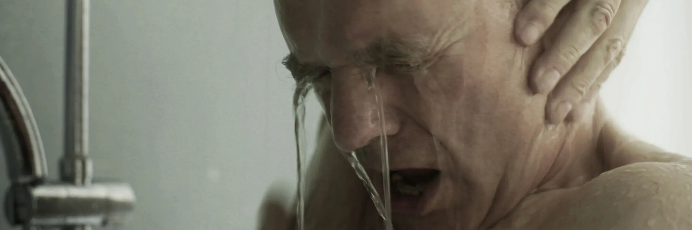 Gesicht eines Mannes unter einer Dusche